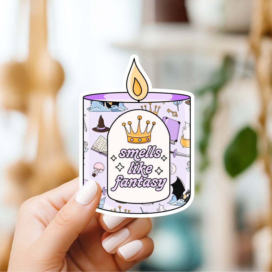 Sticker of a candle with 'smells like fantasy' text held by a hand.