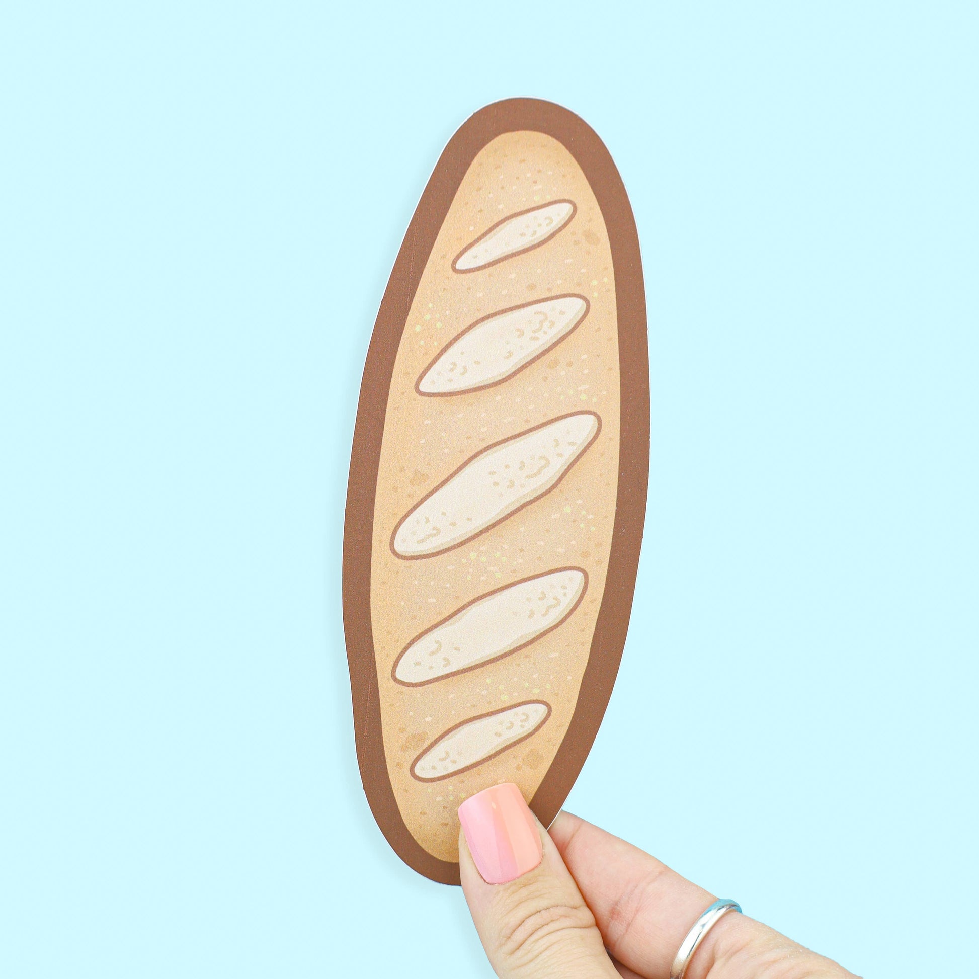 Wooden bread-shaped cutting board held by a hand on a light blue background