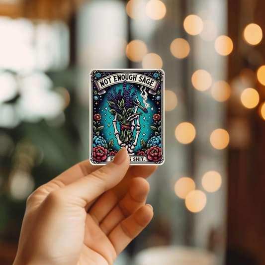 Hand holding a tarot card with 'Not Enough Sage' text against a blurred bokeh background