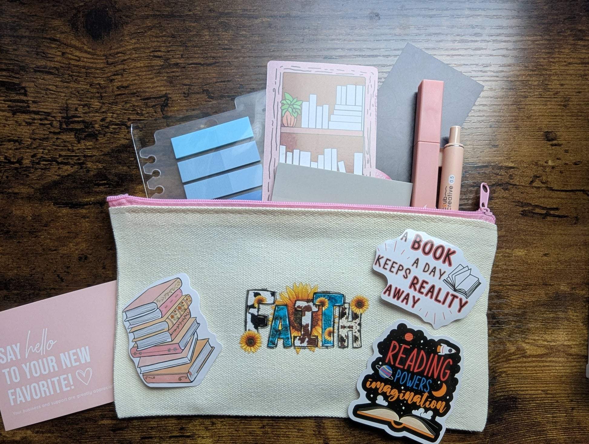 Pouch with stationery items and decorative stickers on a wooden surface