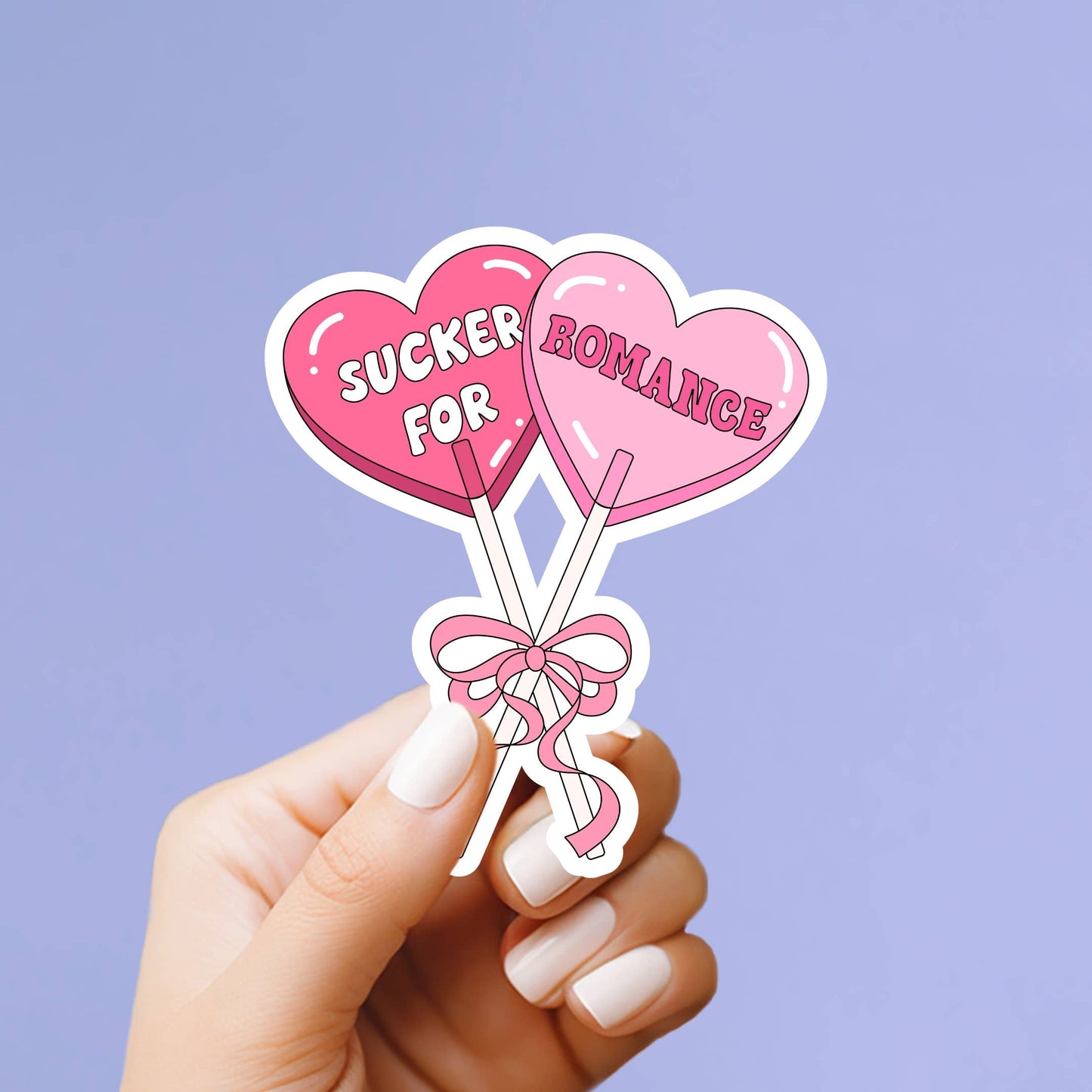 Heart-shaped lollipops with 'Sucker for Romance' text held by a hand against a purple background