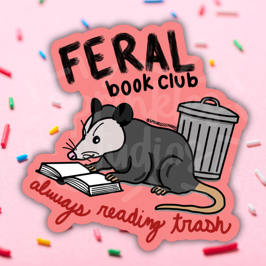 Sticker with a possum reading a book and a trash can, labeled 'Feral Book Club: always reading trash', on a pink background with colorful sprinkles.