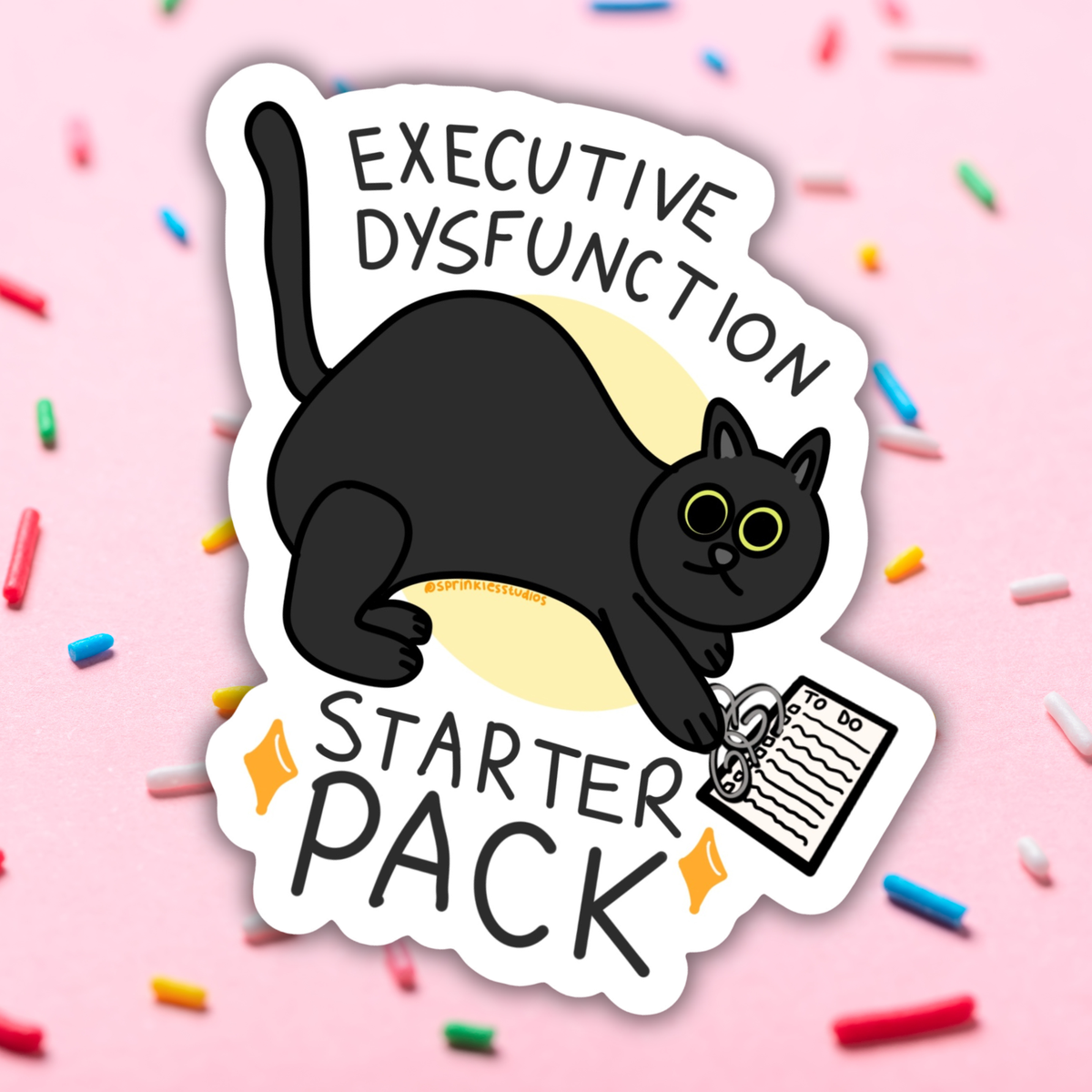 A die-cut sticker featuring a cartoon black cat holding a notepad with the text 'EXECUTIVE DYSFUNCTION STARTER PACK' on a pink background with scattered colorful sprinkles.