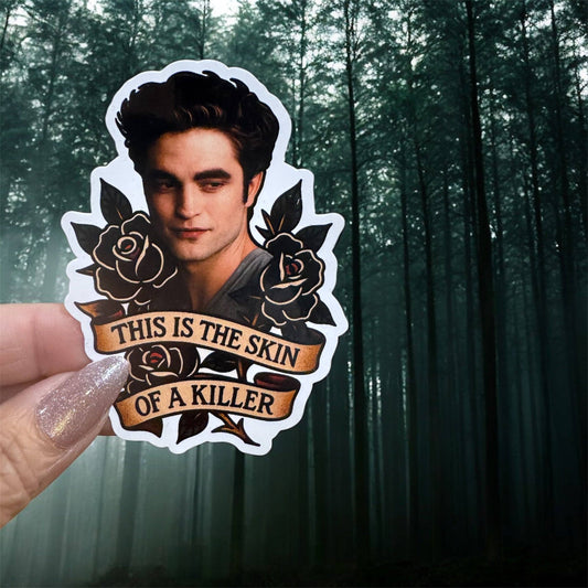 A die-cut sticker featuring a portrait of Edward Carter from The Twilight Saga, with black roses and the text 'THIS IS THE SKIN OF A KILLER' on a tan banner, held by a hand against a dark misty forest background.