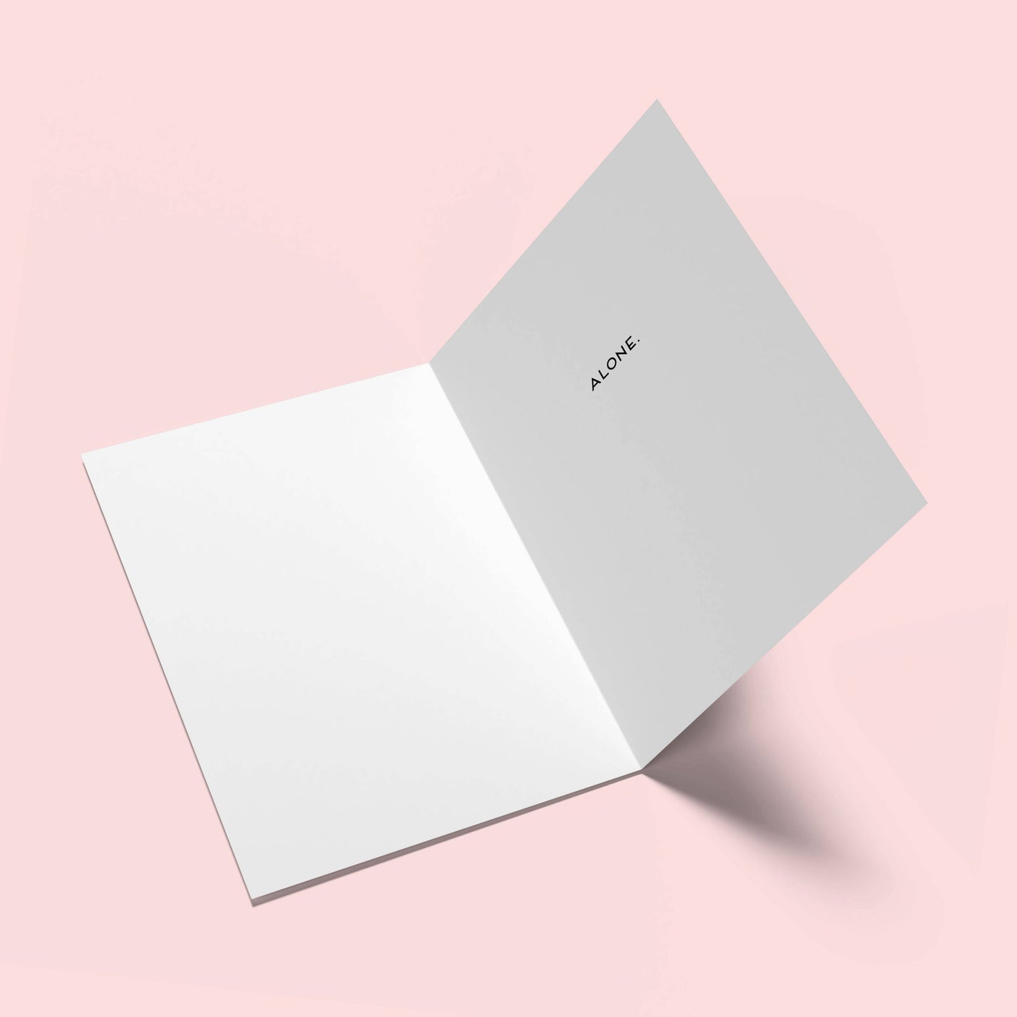 Two greeting cards on a pink background, one open with 'ALONE' text.