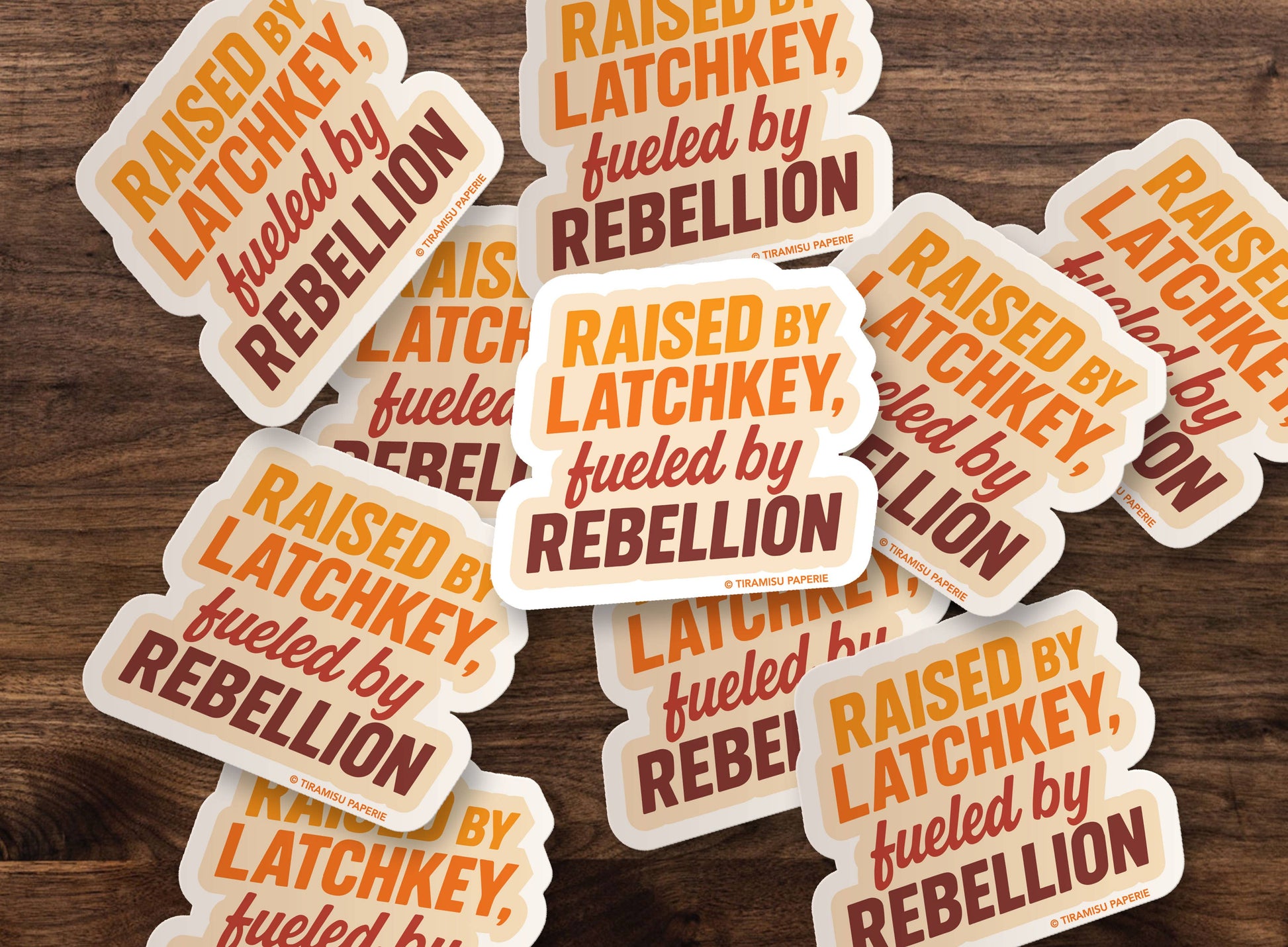 Multiple 'Raised by Latchkey, fueled by Rebellion' stickers on a wooden surface
