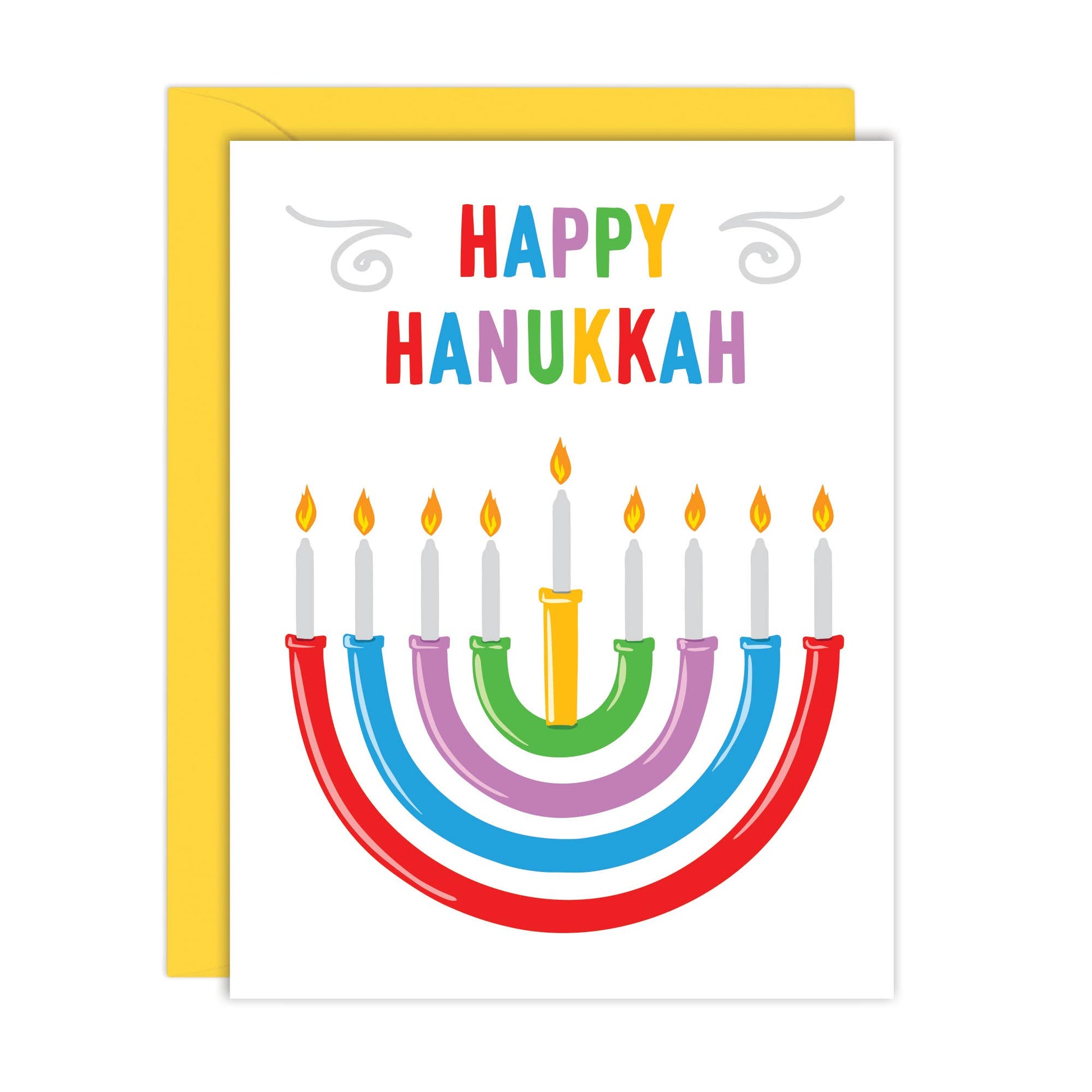A Hanukkah greeting card with a white front, colorful rainbow text reading “HAPPY HANUKKAH,” and a stylized menorah with lit candles. A yellow envelope is partially visible behind the card on a white background.