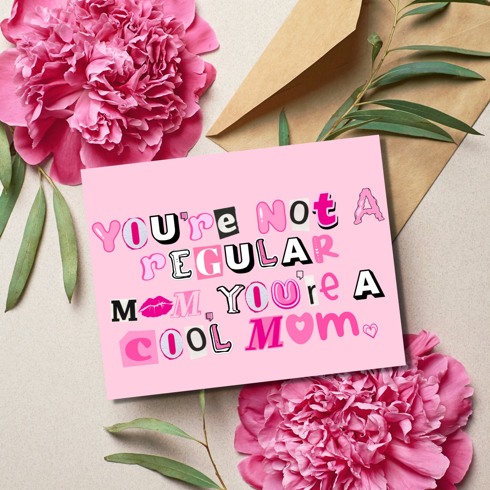 Pink card with text 'You're not a regular mom, you're a cool mom' surrounded by pink flowers and green leaves on a beige background.