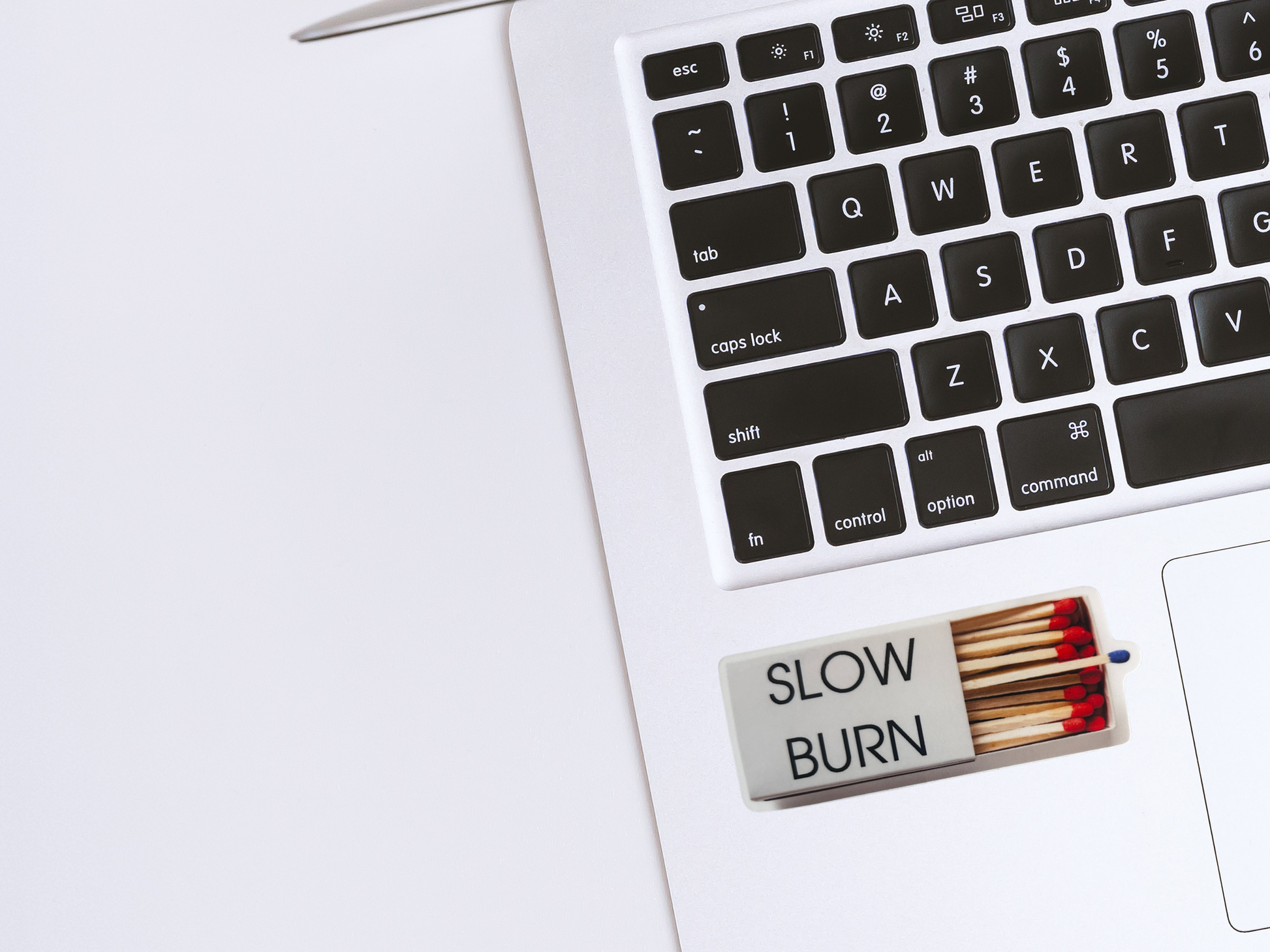 Matches labeled 'SLOW BURN' on a laptop keyboard with a white background