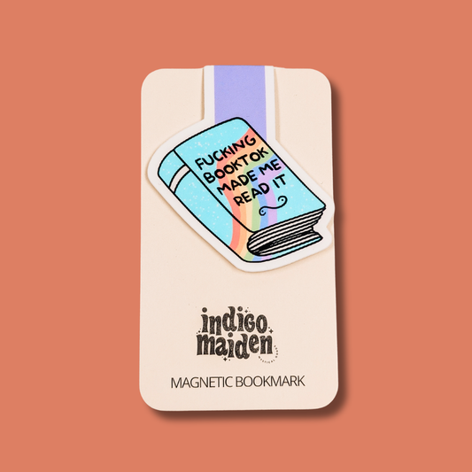 Magnetic bookmark with colorful design and text on a beige card, against a brown background