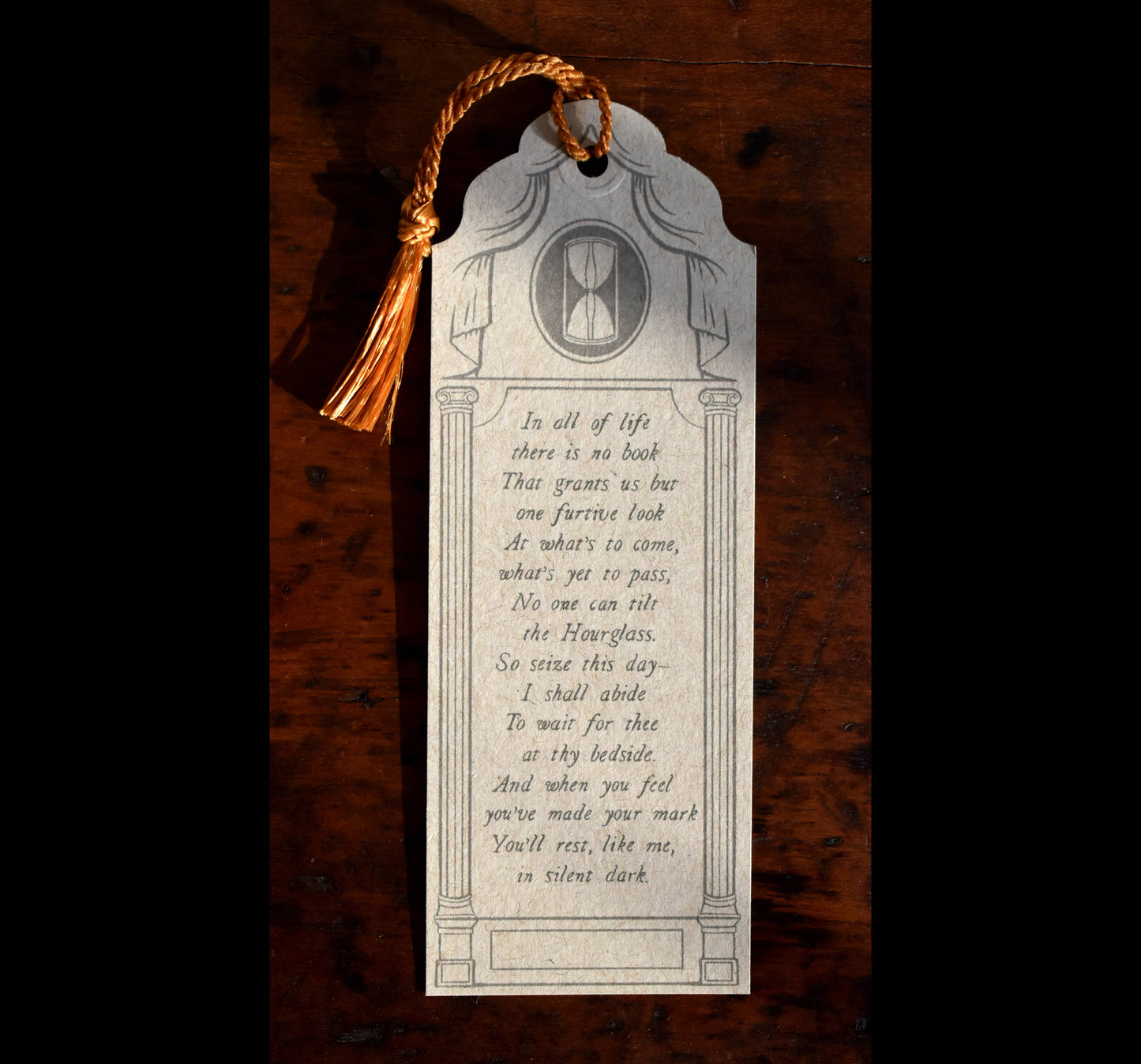 Decorative bookmark with text and tassel on a wooden background