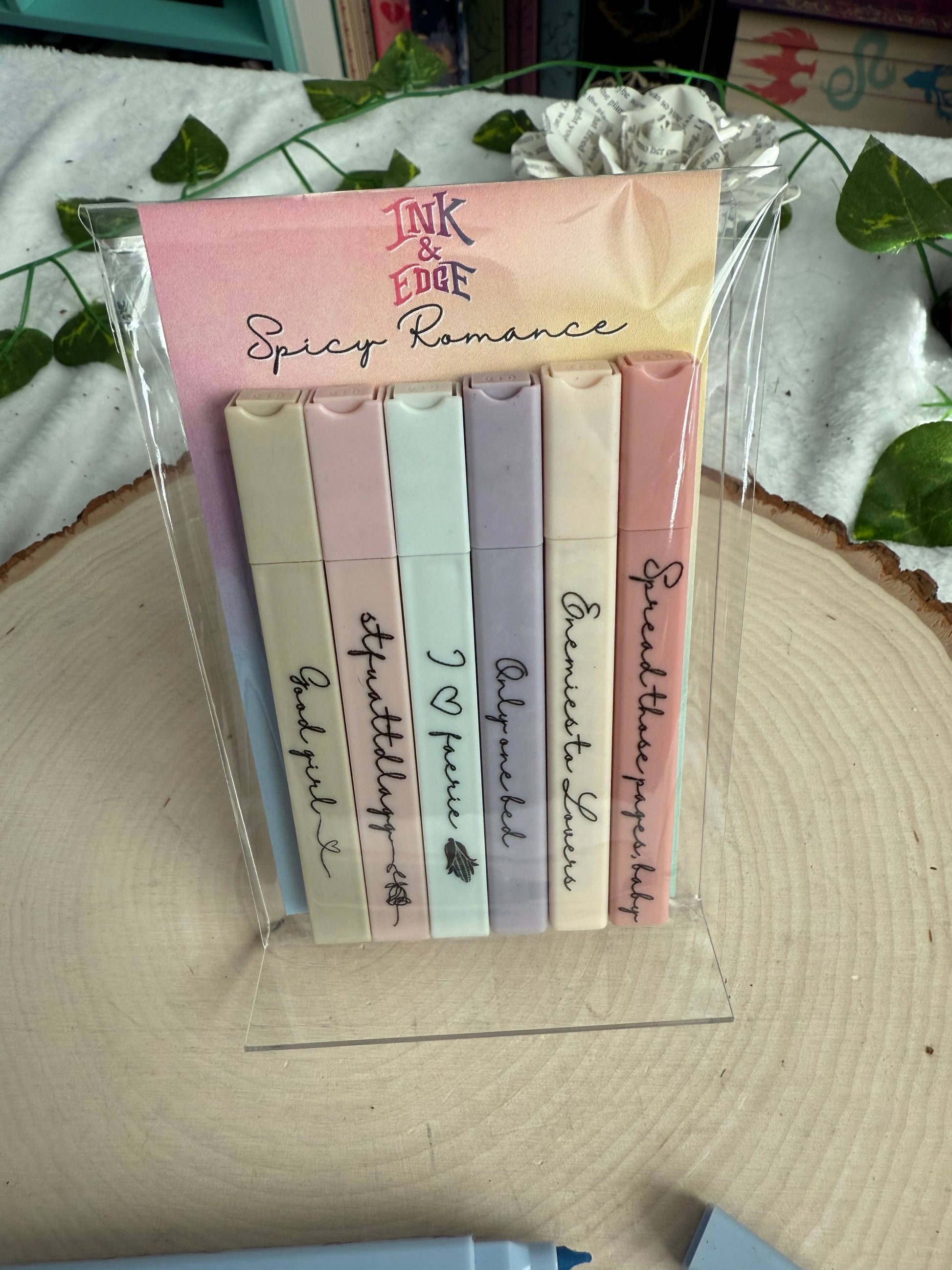 Set of colorful sticky notes with text on a clear stand, placed on a wooden surface with greenery in the background.