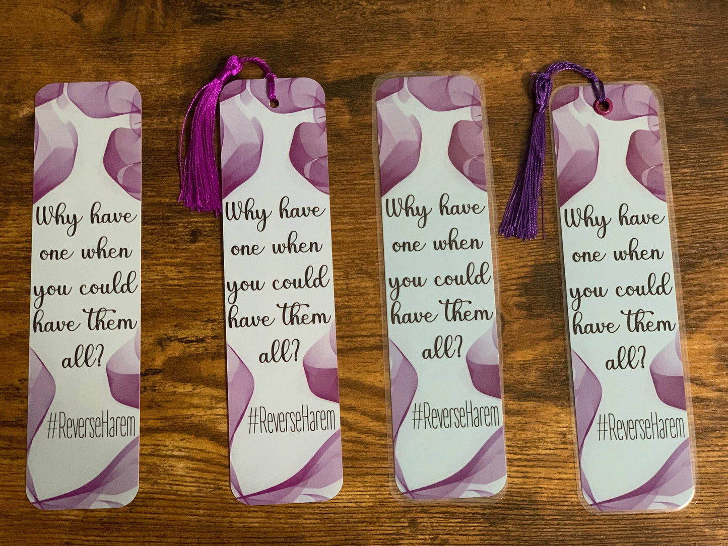 Four identical bookmarks with a purple tassel on a wooden surface
