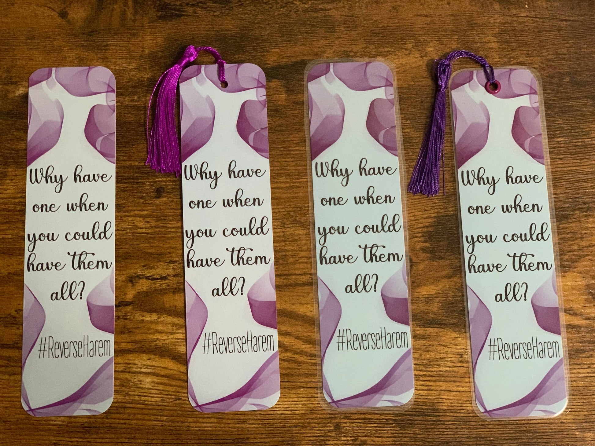 Four identical bookmarks with a purple tassel on a wooden surface