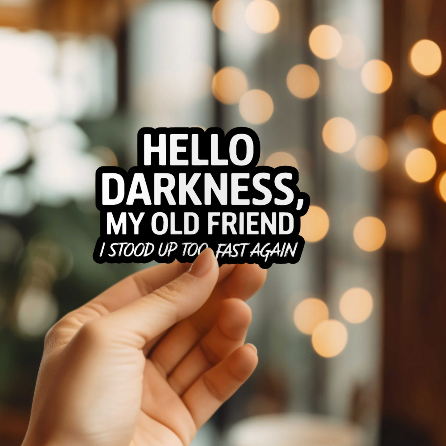 Hand holding a sign with text 'HELLO DARKNESS, MY OLD FRIEND I STOOD UP TOO FAST AGAIN' against a blurred bokeh background.
