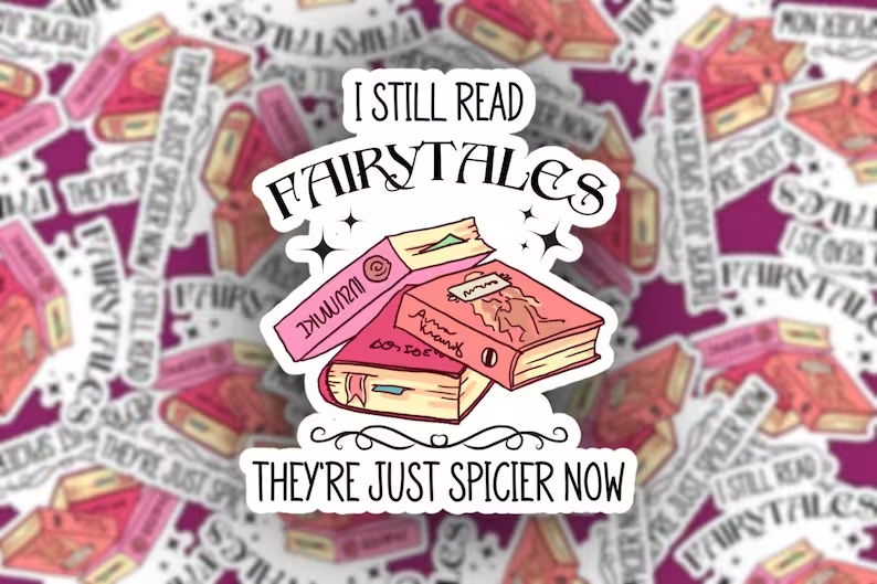 A die-cut sticker featuring an illustration of three pink and beige books with the text 'I STILL READ FAIRYTALES' above and 'THEY'RE JUST SPICIER NOW' below, shown centered over a blurred repeating background of the same sticker design.