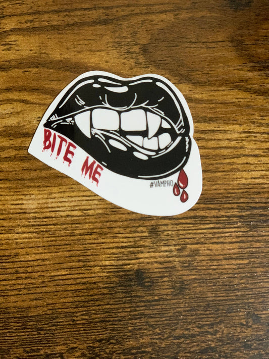 Sticker with a mouth graphic and 'Bite Me' text on a wooden surface